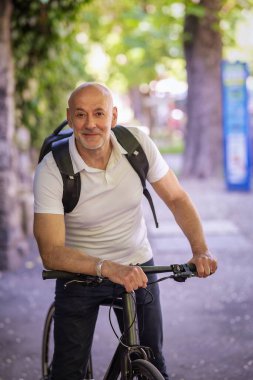 Sokakta bisiklet kullanan orta yaşlı bir adam. Banliyö çalışanı işe gidiyor ve günlük kıyafetler giyiyor.. 