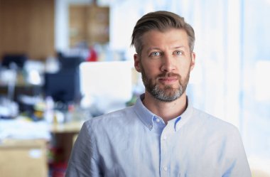 İçeride duran kendinden emin orta yaşlı bir adamın portresi. Orta yaşlı bir adam tişört giyiyor ve kameraya bakıyor..