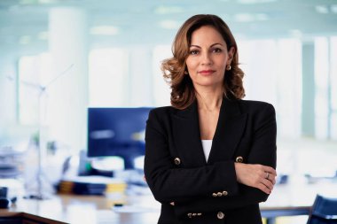 Ofiste duran kendine güvenen bir iş kadını. Profesyonel kadın iş kıyafeti giyiyor ve kameraya bakıyor.. 