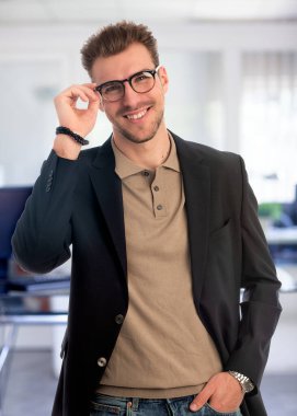 Görevde duran başarılı genç iş adamının portresi. Profesyonel iş adamı kameraya bakıyor ve gülümsüyor..