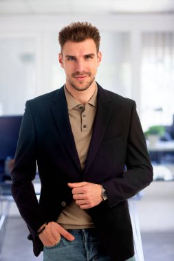 Görevde duran başarılı genç iş adamının portresi. Profesyonel iş adamı kameraya bakıyor ve gülümsüyor..