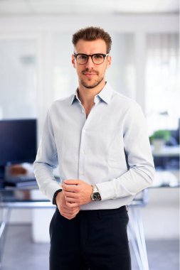 Görevde duran başarılı genç iş adamının portresi. Profesyonel iş adamı kameraya bakıyor ve gülümsüyor..