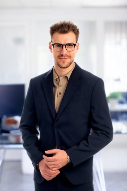 Görevde duran başarılı genç iş adamının portresi. Profesyonel iş adamı kameraya bakıyor ve gülümsüyor..