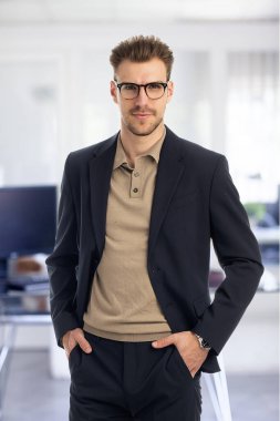 Görevde duran başarılı genç iş adamının portresi. Profesyonel iş adamı kameraya bakıyor ve gülümsüyor..