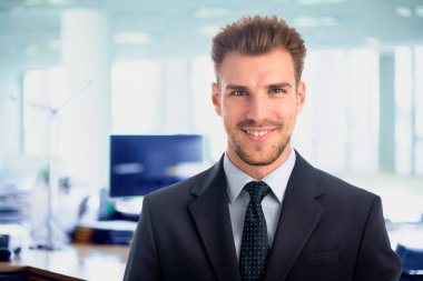 Görevde duran başarılı genç iş adamının portresi. Profesyonel iş adamı kameraya bakıyor ve gülümsüyor..