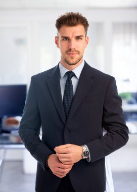 Görevde duran başarılı genç iş adamının portresi. Profesyonel iş adamı kameraya bakıyor ve gülümsüyor..