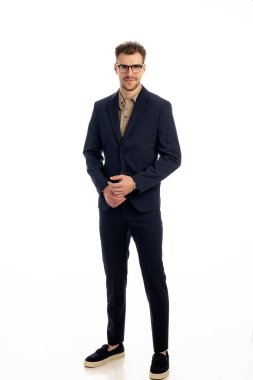 İzole edilmiş beyaz arka plana karşı duran yakışıklı bir gencin stüdyo fotoğrafı. Kendine güvenen erkek takım elbiseli ve kameraya bakıyor. Uzayı kopyala İzole edilmiş arka plan. Tam uzunluk. 