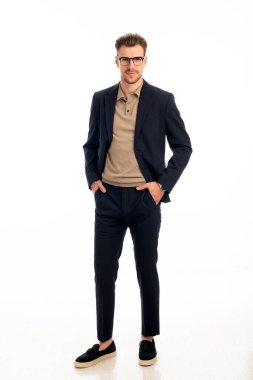 İzole edilmiş beyaz arka plana karşı duran yakışıklı bir gencin stüdyo fotoğrafı. Kendine güvenen erkek takım elbiseli ve kameraya bakıyor. Uzayı kopyala İzole edilmiş arka plan. Tam uzunluk. 