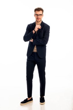 İzole edilmiş beyaz arka plana karşı duran yakışıklı bir gencin stüdyo fotoğrafı. Kendine güvenen erkek takım elbiseli ve kameraya bakıyor. Uzayı kopyala İzole edilmiş arka plan. Tam uzunluk. 