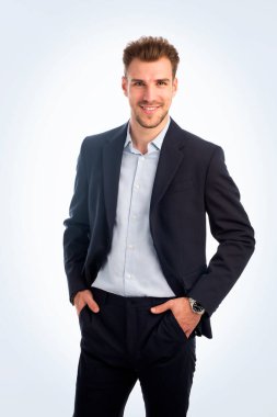 İzole edilmiş beyaz arka plana karşı duran yakışıklı bir gencin stüdyo fotoğrafı. Kendine güvenen erkek takım elbiseli ve kameraya bakıyor. Uzayı kopyala İzole edilmiş arkaplan. 