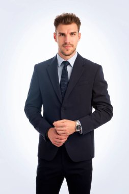 İzole edilmiş beyaz arka plana karşı duran yakışıklı bir gencin stüdyo fotoğrafı. Kendine güvenen erkek takım elbiseli ve kameraya bakıyor. Uzayı kopyala İzole edilmiş arkaplan. 