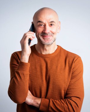 Tecrit edilmiş arka planda akıllı telefon kullanan orta yaşlı bir adamın stüdyo portresi. Boşluğu kopyala. 