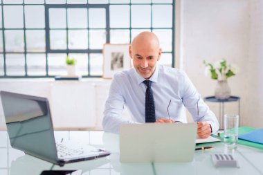 Ofis masasında dizüstü bilgisayar kullanan bir iş adamı. Modern bir ofiste çalışan profesyonel bir adam..