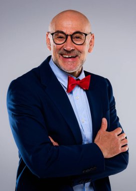 Tecrit edilmiş arka planda duran kıdemli iş adamının stüdyo portresi. Uzayı kopyala Kendine güvenen erkek takım elbise giyiyor ve gülüyor..