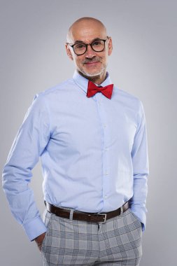 Gözlüklü ve şık giyinmiş gülümseyen son sınıf öğrencisinin portresi. Kendine güvenen erkek kameraya bakıyor ve izole edilmiş arka plana gülümsüyor..