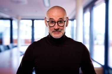 Kendinden emin orta yaşlı bir iş adamı hayretle kameraya bakıyor. Gündelik kıyafet ve gözlük takan kendinden emin bir erkek.. 