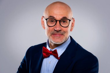 Tecrit edilmiş arka planda duran son sınıf öğrencisinin stüdyo portresi. Uzayı kopyala Tişört ve papyon takan kendinden emin bir erkek.. 