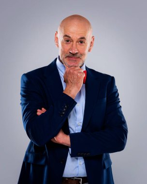 Tecrit edilmiş arka planda duran yaşlı adamın stüdyo portresi. Uzayı kopyala Kendine güvenen erkek takım elbiseli ve düşünceli görünüyor..