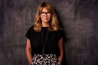 Gülümseyen olgun bir kadının portresi. Kendine güveni tam, sarı saçlı, esmer bir kadın. Siyah gömlek ve etek giyen çekici bir kadın. Boşluğu kopyala. 