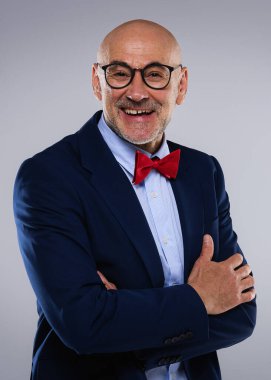 Tecrit edilmiş arka planda duran kıdemli iş adamının stüdyo portresi. Uzayı kopyala Kendine güvenen erkek takım elbise giyiyor ve gülüyor..