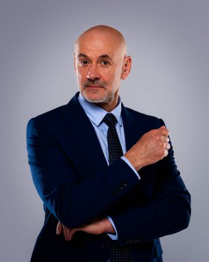 Tecrit edilmiş arka planda duran kıdemli iş adamının stüdyo portresi. Uzayı kopyala Kendine güvenen erkek takım elbiseli ve kameraya bakıyor..