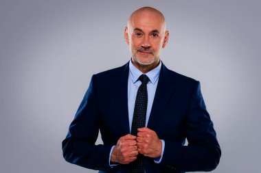 Tecrit edilmiş arka planda duran yaşlı adamın stüdyo portresi. Uzayı kopyala Kendine güvenen erkek takım elbiseli ve kameraya gülümsüyor..