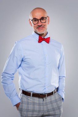 Gözlüklü ve şık giyinmiş gülümseyen son sınıf öğrencisinin portresi. Kendine güvenen erkek kameraya bakıyor ve izole edilmiş arka plana gülümsüyor..