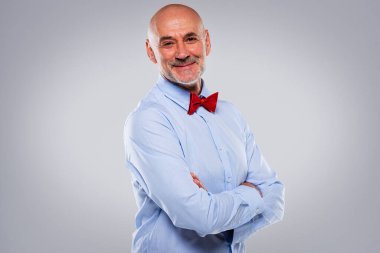 Kırmızı papyon takan ve şık giyinen gülümseyen son sınıf öğrencisinin portresi. Kendine güvenen erkek kameraya bakıyor ve izole edilmiş arka plana gülümsüyor..