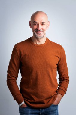 Gri arka planda duran kendine güvenen bir adamın vesikalığı. Süveter giyen ve kameraya gülümseyen bir erkek. Boşluğu kopyala. 