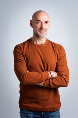 Gri arka planda duran kendine güvenen bir adamın vesikalığı. Süveter giyen ve kameraya gülümseyen bir erkek. Boşluğu kopyala. 