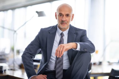 İdari işadamı ofiste oturuyor. Kendine güvenen erkek takım elbiseli ve düşünceli görünüyor. Yakın çekim.. 