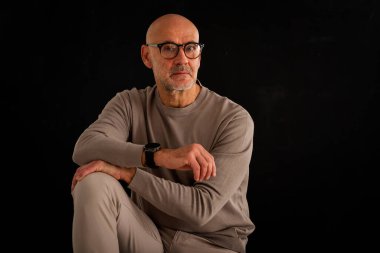 Düşünceli, orta yaşlı, gözlüklü ve sıradan kıyafetler giyen bir adamın stüdyo fotoğrafı. Kendine güvenen bir erkek kameraya bakıyor ve derin düşünce ve karar verme mekanizmasını öneriyor. Boşluğu kopyala. 