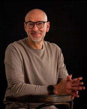 Düşünceli, orta yaşlı, gözlüklü ve sıradan kıyafetler giyen bir adamın stüdyo fotoğrafı. Kendinden emin bir erkek kameraya bakıyor ve gülümsüyor. İzole edilmiş arka plan. Boşluğu kopyala. 