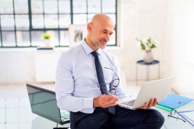 Ofiste oturup dizüstü bilgisayar kullanan kendine güvenen bir iş adamı. Video görüşmesi yapan profesyonel bir adam. Boşluğu kopyala.