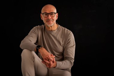 Düşünceli, orta yaşlı, gözlüklü ve sıradan kıyafetler giyen bir adamın stüdyo fotoğrafı. Kendinden emin bir erkek kameraya bakıyor ve gülümsüyor. İzole edilmiş arka plan. Boşluğu kopyala. 