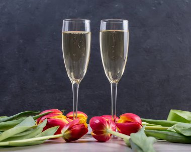 Bir bardak şampanya ve arka planda bir buket gül..