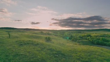 Çimenli tepeler günbatımına karşı yüksekten alınır