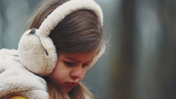 在秋天的公园里 一个戴着白色耳机的女孩走在公园里 — 图库视频影像