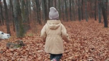 child runs with a dog in the autumn forest
