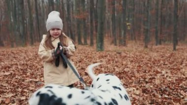 child runs with a dog in the autumn forest