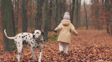 child runs with a dog in the autumn forest