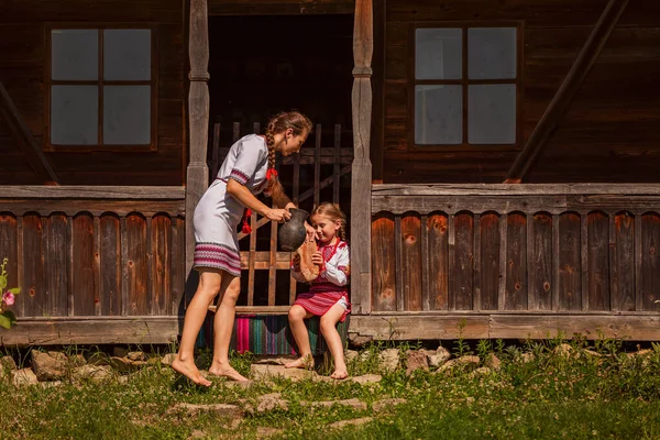 mother and daughter in Ukrainian folk dresses on the threshold of the house.