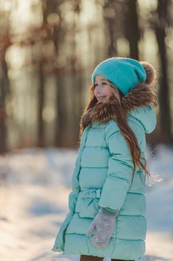 Turkuazlı bir kız ve kış ormanında bir şapka dikey olarak vuruldu.