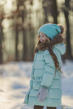 Turkuazlı bir kız ve kış ormanında bir şapka dikey olarak vuruldu.