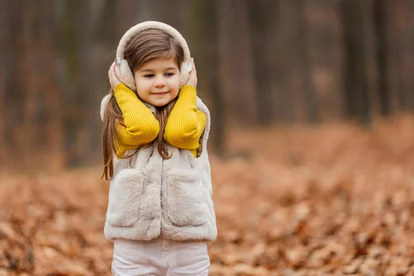 ヘッドフォンの女の子が秋の森を歩き — ストック写真