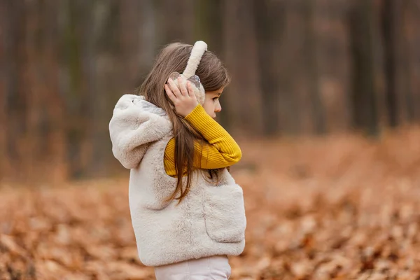 ヘッドフォンの女の子が秋の森を歩き — ストック写真