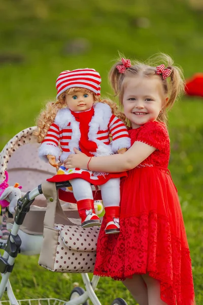 女の子は自然に人形と遊ぶ 彼女の腕の中で彼女を保持 — ストック写真