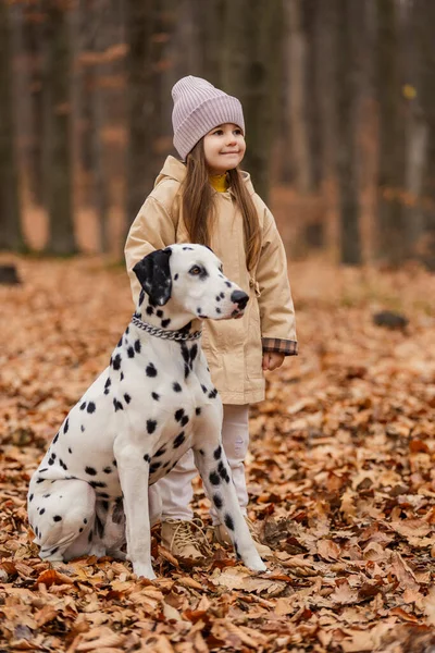 girl with a Dalmatian dog in the autumn forest