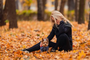 Sonbahar parkında küçük köpeğiyle bir kız.