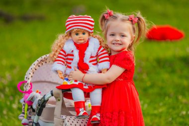 The girl plays with a doll in nature, holding her in her arms